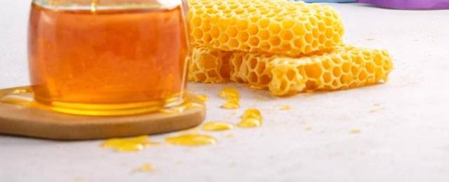 Jar of honey beside honeycomb